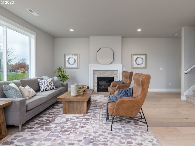 living area with visible vents, stairs, a stone fireplace, recessed lighting, and light wood-style flooring