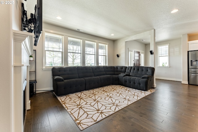 living area featuring dark wood-type flooring, a textured ceiling, visible vents, and baseboards