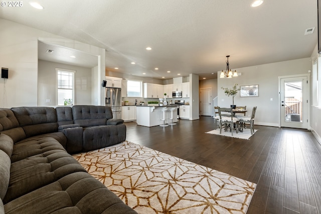 living room featuring an inviting chandelier, dark wood-style flooring, visible vents, and recessed lighting