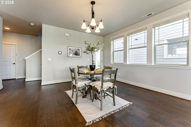 dining space featuring baseboards, hardwood / wood-style flooring, visible vents, and a notable chandelier
