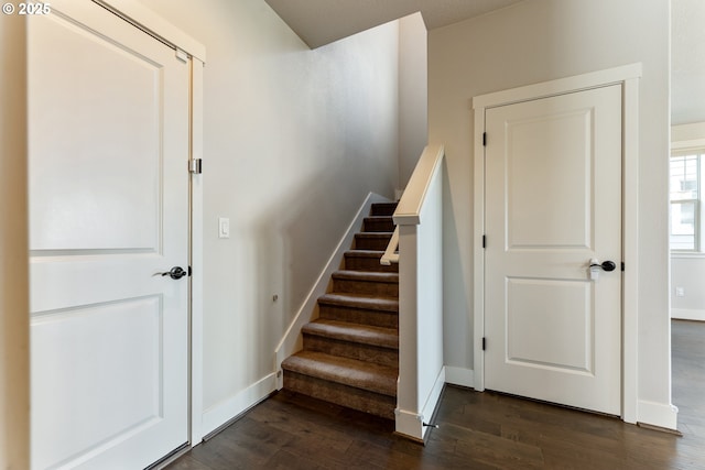 staircase featuring baseboards and wood finished floors