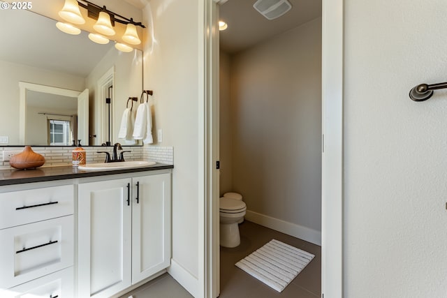 bathroom with visible vents, toilet, vanity, baseboards, and decorative backsplash