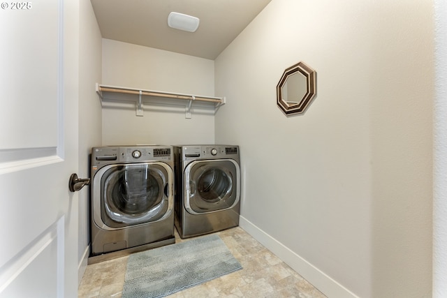 washroom with washing machine and dryer, baseboards, and laundry area