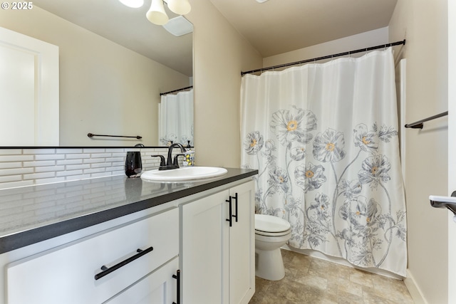 bathroom with decorative backsplash, vanity, stone finish floor, and toilet