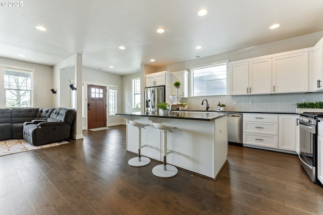 kitchen with white cabinets, dark countertops, appliances with stainless steel finishes, and open floor plan