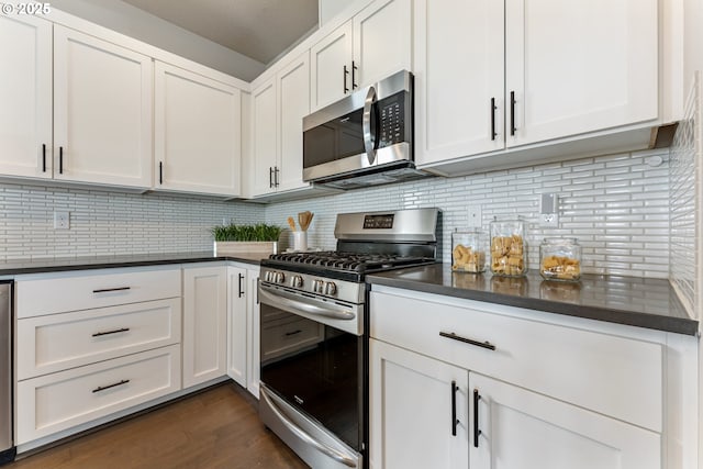 kitchen featuring white cabinets, tasteful backsplash, dark wood finished floors, dark countertops, and appliances with stainless steel finishes