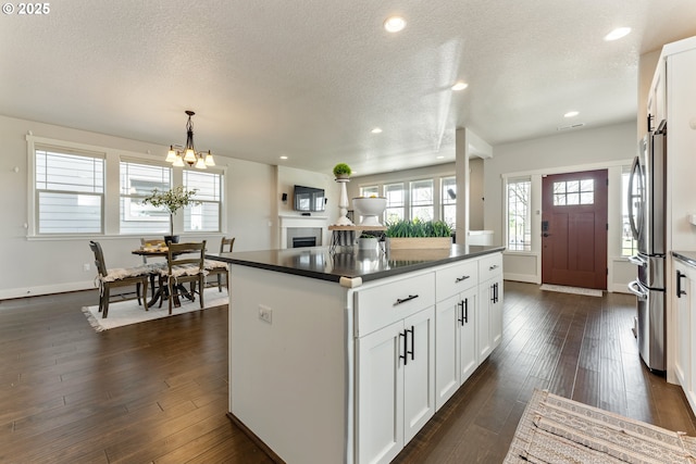 kitchen with white cabinets, a textured ceiling, dark wood finished floors, dark countertops, and freestanding refrigerator