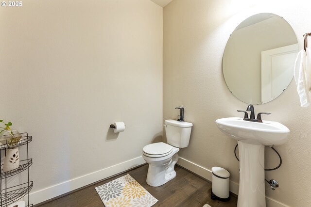 bathroom with a sink, toilet, wood finished floors, and baseboards