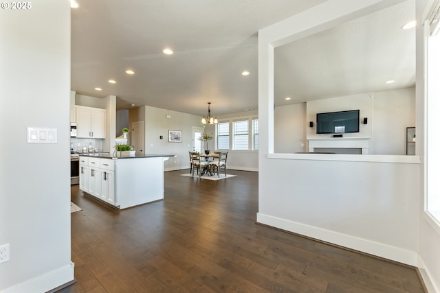 kitchen featuring stainless steel electric range oven, dark countertops, baseboards, a notable chandelier, and white cabinetry