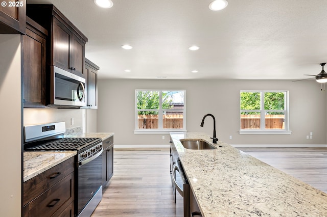 kitchen with a wealth of natural light, stainless steel appliances, dark brown cabinets, and a sink