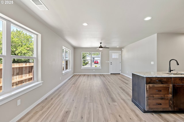 unfurnished living room featuring a sink, recessed lighting, ceiling fan, light wood-style flooring, and baseboards