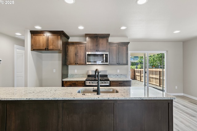 kitchen with light wood-style flooring, recessed lighting, baseboards, a sink, and appliances with stainless steel finishes