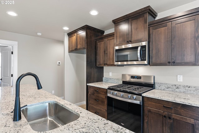 kitchen with dark brown cabinets, stainless steel appliances, recessed lighting, and a sink