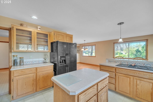 kitchen featuring glass insert cabinets, black appliances, light brown cabinetry, and light countertops