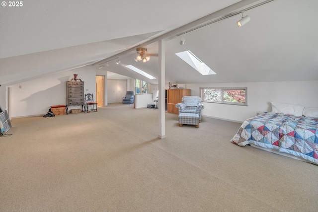 carpeted bedroom featuring track lighting and vaulted ceiling with skylight