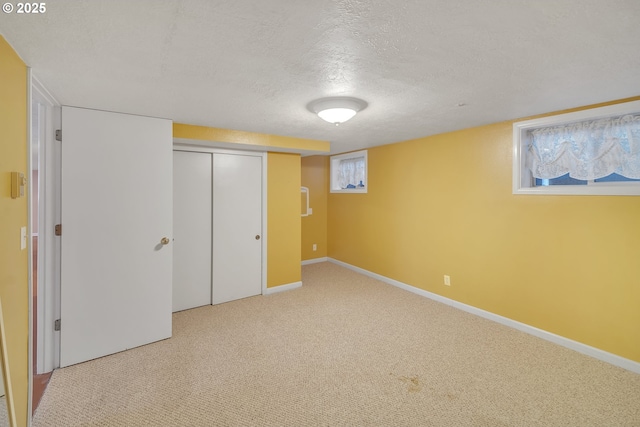 below grade area featuring a textured ceiling, baseboards, and carpet floors
