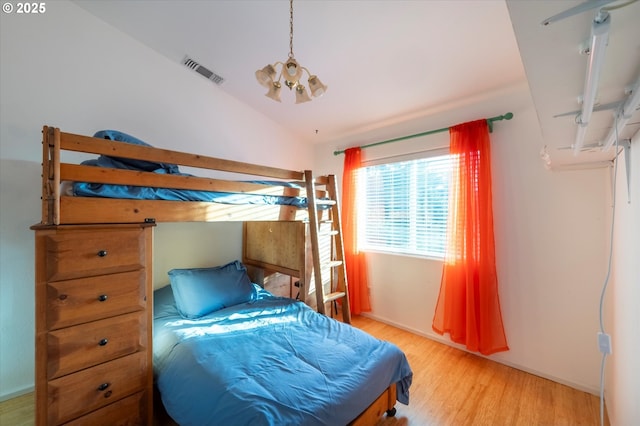 bedroom featuring lofted ceiling, light hardwood / wood-style floors, and a notable chandelier