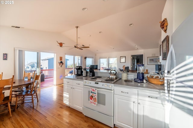 kitchen with vaulted ceiling, electric stove, white cabinets, fridge, and light hardwood / wood-style flooring