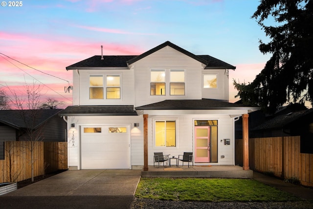 view of front of home featuring an attached garage, concrete driveway, and fence