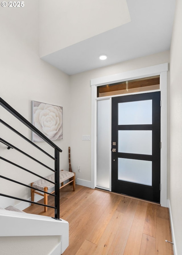 entryway with stairway, light wood-style flooring, and baseboards