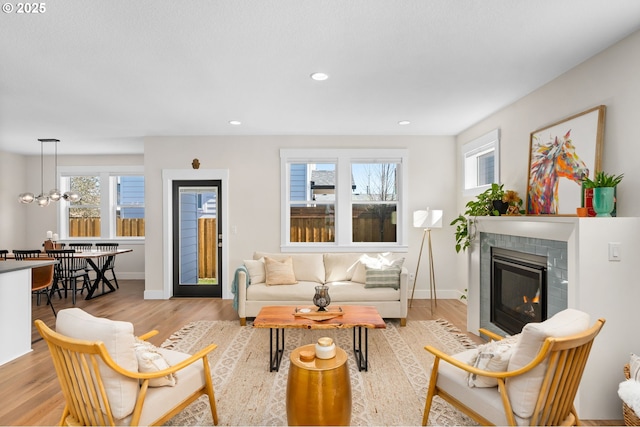 living room featuring recessed lighting, light wood-type flooring, a fireplace with flush hearth, and a healthy amount of sunlight