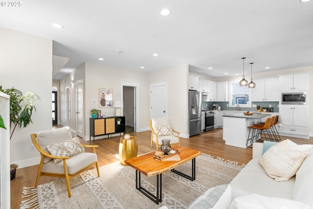 living area featuring light wood-style flooring, recessed lighting, and baseboards