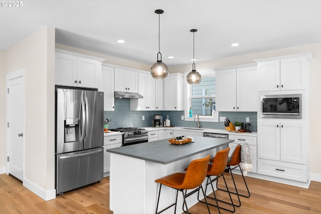 kitchen featuring under cabinet range hood, white cabinetry, appliances with stainless steel finishes, and a sink