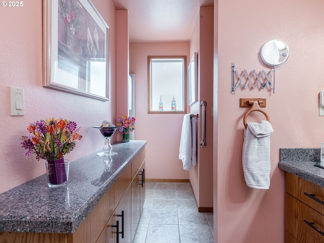 bathroom with tile patterned flooring, baseboards, and vanity