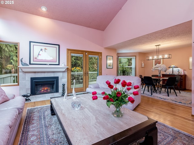 living room with vaulted ceiling, french doors, a textured ceiling, and wood finished floors