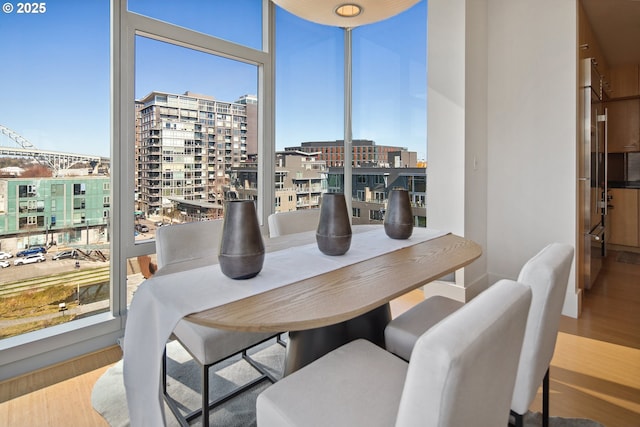 dining room featuring a city view, a wall of windows, and wood finished floors