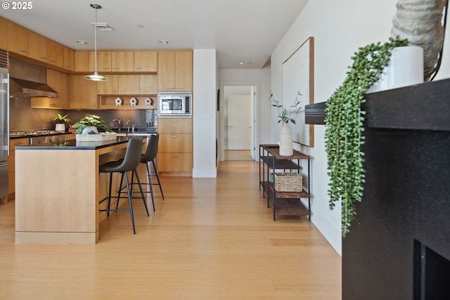 kitchen with visible vents, light wood-style flooring, a kitchen breakfast bar, a center island, and stainless steel appliances