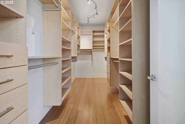 walk in closet with light wood finished floors