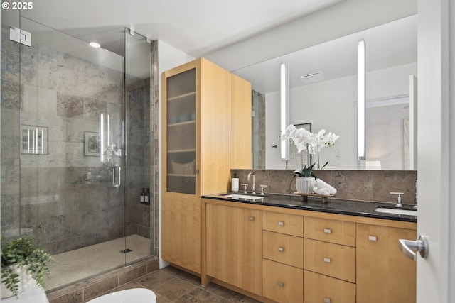 bathroom with double vanity, a stall shower, tasteful backsplash, and a sink