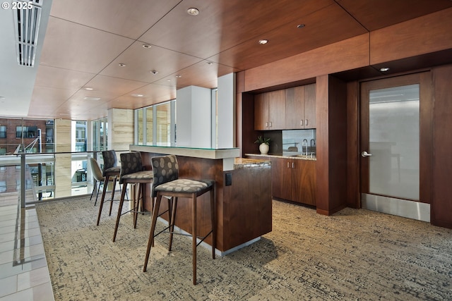 kitchen featuring a kitchen bar, a sink, backsplash, recessed lighting, and light countertops