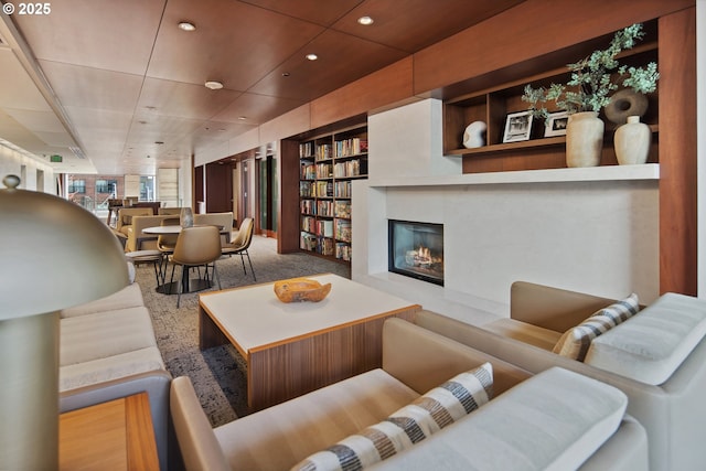 living room with a glass covered fireplace, built in features, recessed lighting, and carpet floors