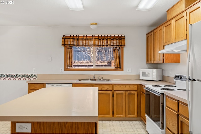 kitchen featuring under cabinet range hood, white appliances, a sink, light countertops, and light floors