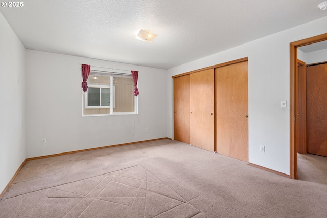 unfurnished bedroom with a closet, carpet flooring, a textured ceiling, and baseboards