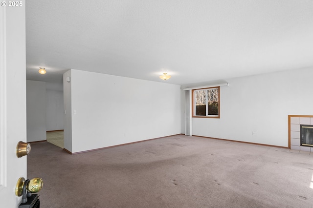 unfurnished living room featuring carpet, a fireplace, and baseboards