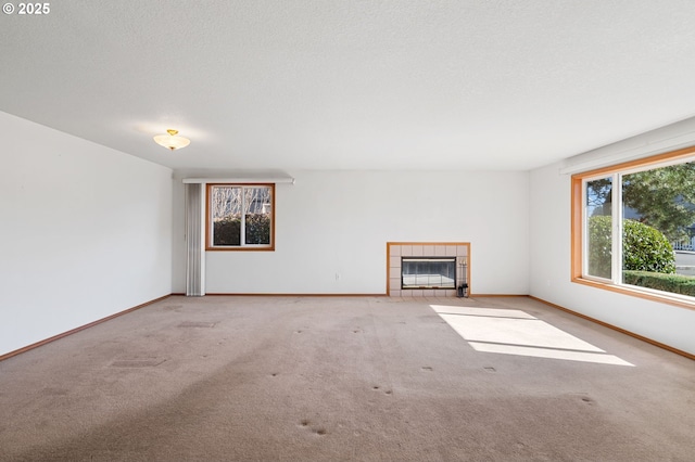 unfurnished living room with carpet floors, a fireplace, baseboards, and a textured ceiling