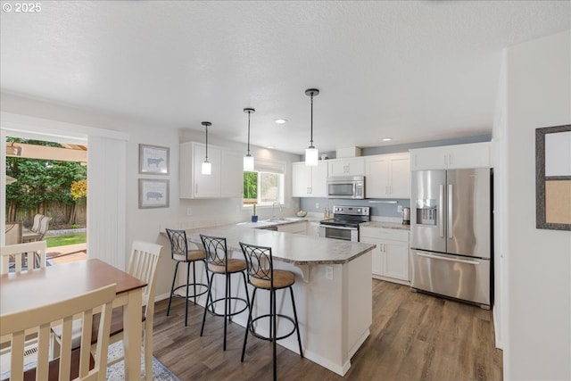 1133 7th St, Lafayette, OR 97127 - kitchen featuring stainless steel appliances, a peninsula, wood finished floors, a breakfast bar, and recessed lighting