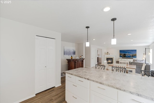 1133 7th St, Lafayette, OR 97127 - kitchen featuring dark wood-style flooring, light countertops, white cabinetry, hanging light fixtures, and a glass covered fireplace