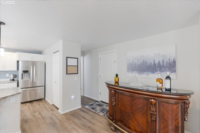 1133 7th St, Lafayette, OR 97127 - kitchen featuring stainless steel refrigerator with ice dispenser, light wood finished floors, white cabinets, and a textured ceiling