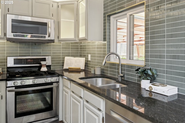 7335 SE 48th Ave, Portland, OR 97206 - kitchen featuring stainless steel appliances, a sink, tasteful backsplash, white cabinets, and dark stone counters