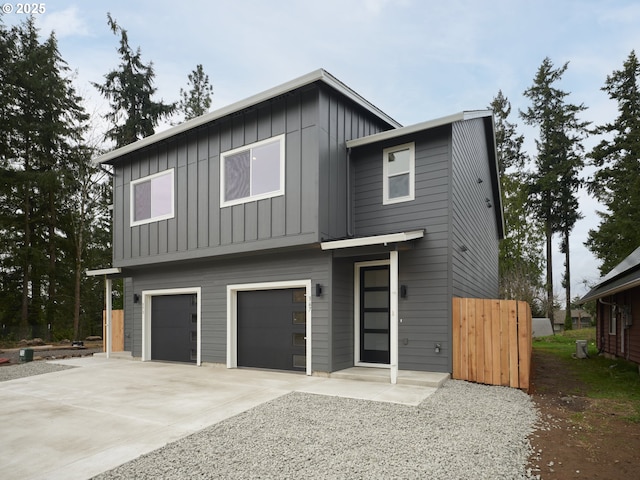 view of front facade featuring board and batten siding, driveway, a garage, and fence