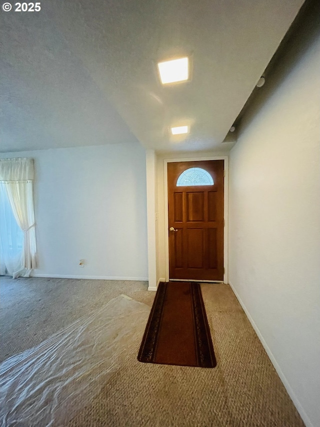 doorway to outside featuring carpet, baseboards, and a textured ceiling