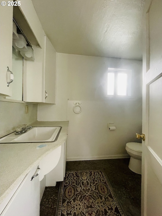 half bath with toilet, vanity, and baseboards