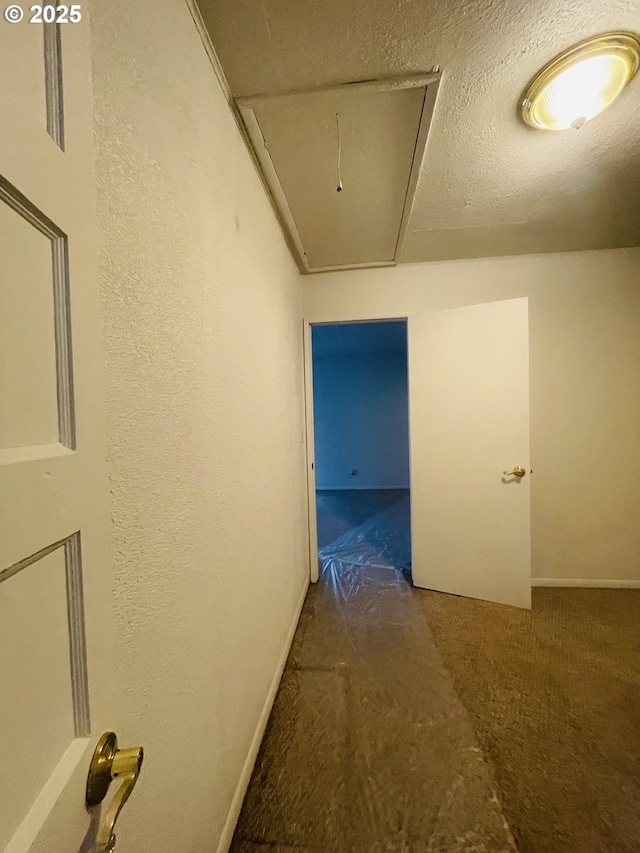 hall featuring a textured ceiling and attic access