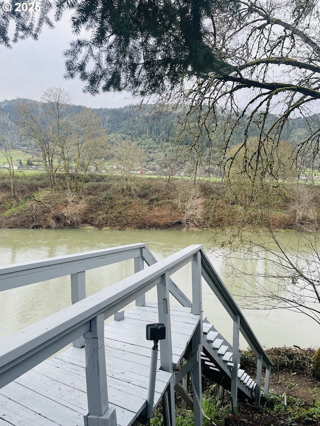 dock area featuring a wooded view and a water view