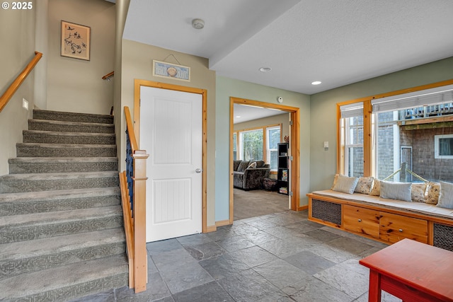 stairs with baseboards, recessed lighting, a textured ceiling, and stone tile floors