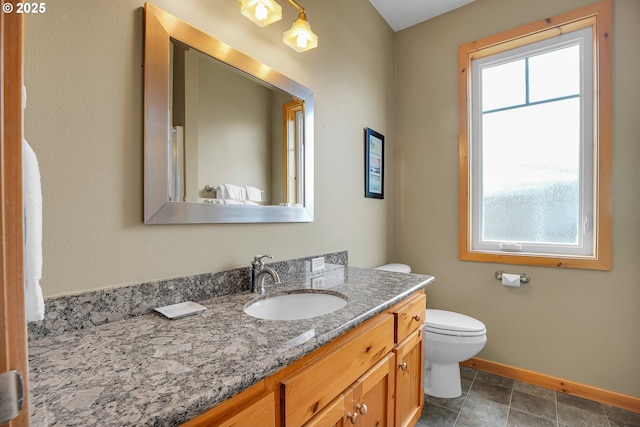 bathroom featuring toilet, baseboards, and vanity